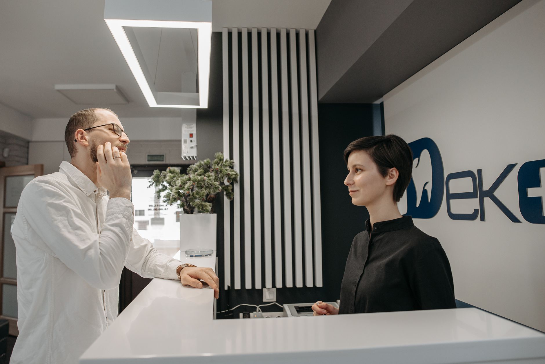 Person talking with a receptionist at a dental clinic front desk