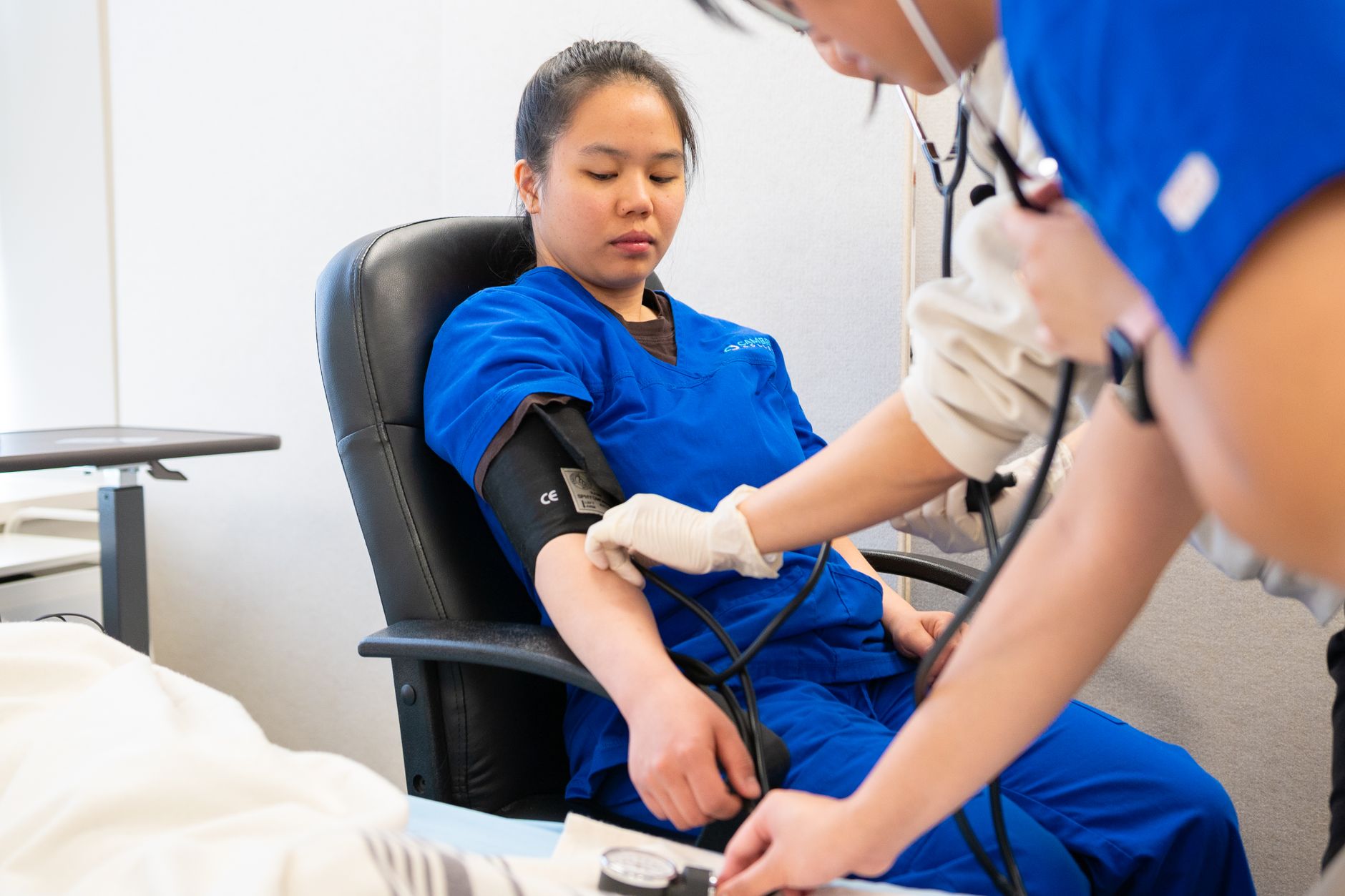Healthcare worker in scrubs checking a patient's blood pressure