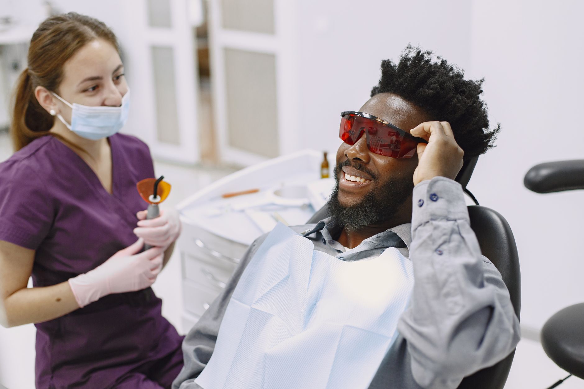 Smiling patient in protective glasses during a dental visit